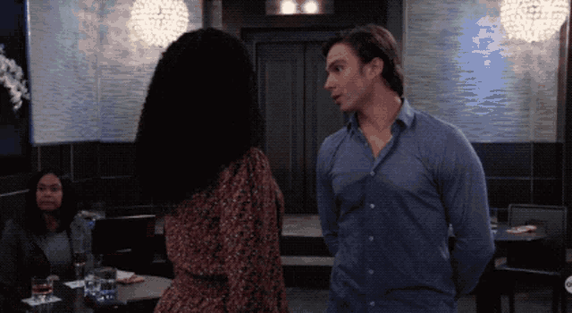 a man in a blue shirt stands next to a woman in a dress in a restaurant