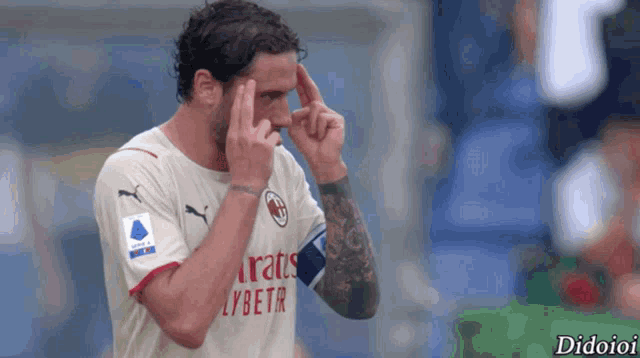 a soccer player wearing a fly emirates jersey holds his hands to his forehead