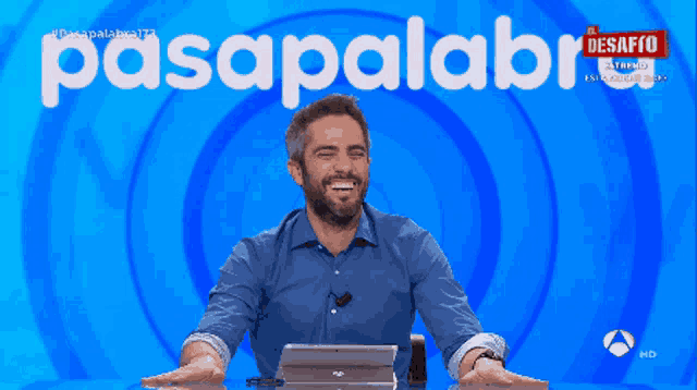 a man sitting in front of a blue background with the word pasapalabra on it