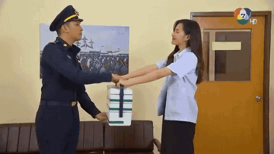 a man in a military uniform is handing a box to a woman in a white shirt