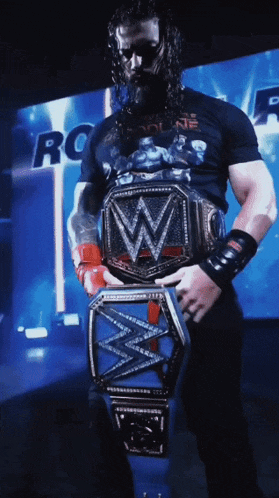 a wrestler is holding a wrestling championship belt with the letter w on it