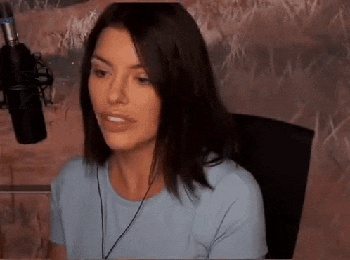a woman is sitting in front of a microphone wearing headphones and a blue shirt .