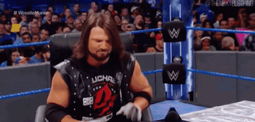 a wrestler is sitting in a chair in front of a crowd .