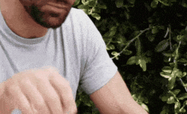 a man with a beard is wearing a white shirt and holding a bottle of water .