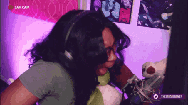 a woman wearing headphones is sitting in front of a computer screen with the words sav cam on the bottom right