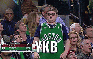 a boy wearing a green boston ykb jersey stands in the crowd