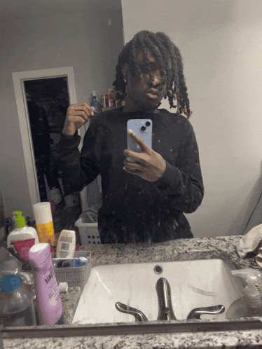 a man taking a picture of himself in a bathroom mirror with a bottle of xtreme shampoo in front of him