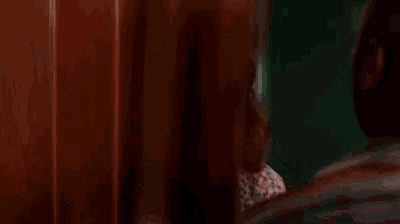 a woman is sitting in front of a window making a funny face .