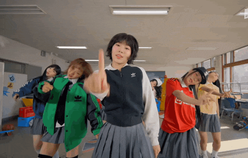 a group of girls are dancing in a classroom and one of them is wearing an adidas jacket