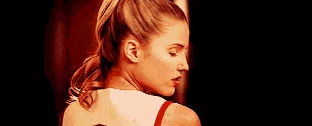 a close up of a woman 's back with her eyes closed and a ponytail .