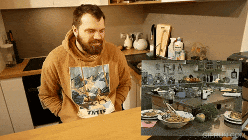 a man wearing a hoodie that says tatry sits in the kitchen
