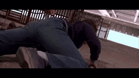 a man is laying on the ground with his legs crossed and a fence in the background .