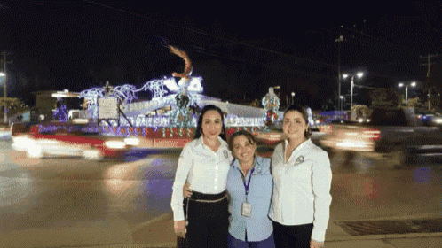 three women are posing for a photo in front of a christmas decoration