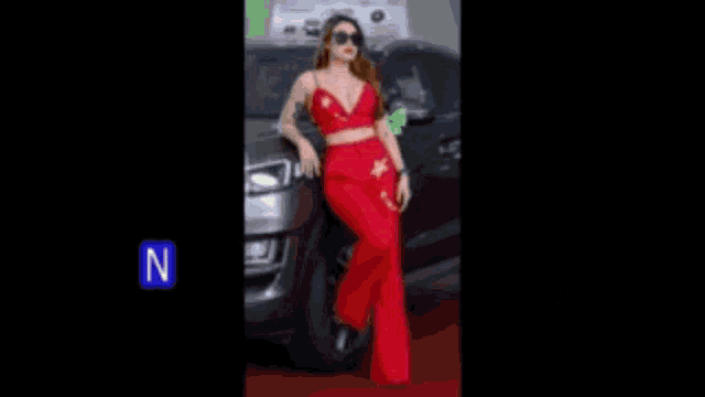 a woman in a red dress is leaning against a car with foreign writing on it .