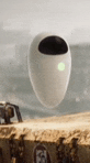 wall e from the movie wall e is flying in the air over a sandy beach .