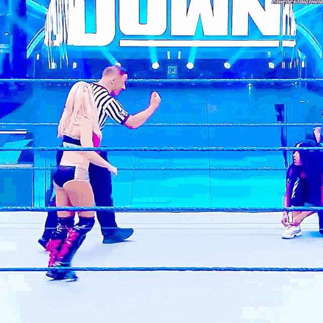 a woman in a wrestling ring with a referee and the word down in the background