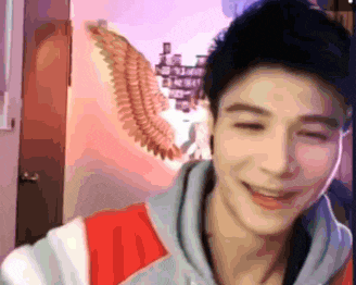 a young man is smiling with his eyes closed in front of a wall with angel wings on it .