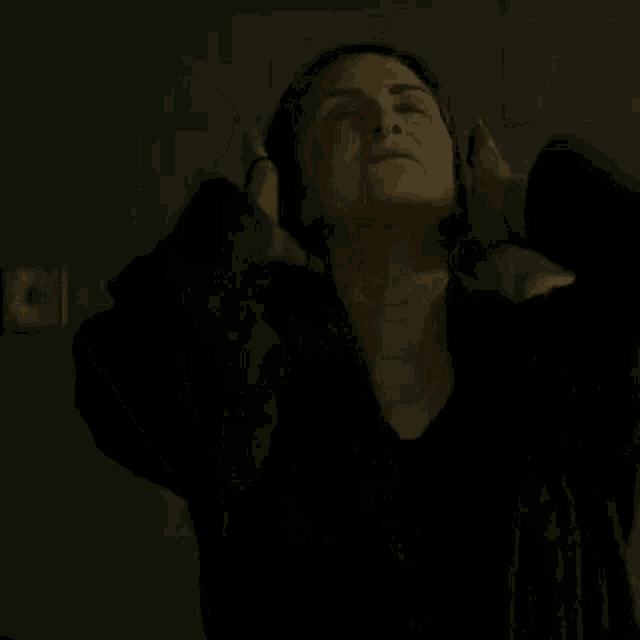 a woman is standing in front of a mirror with her arms outstretched and her eyes closed .