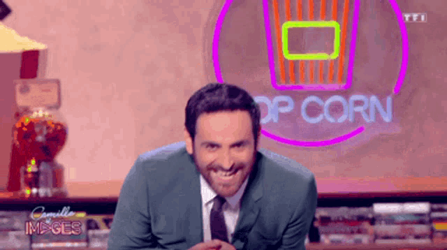 a man in a suit and tie is smiling in front of a popcorn sign