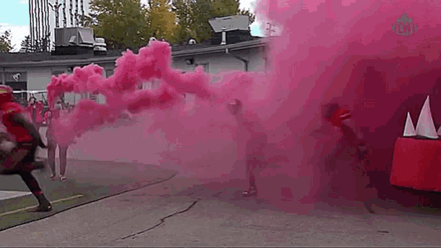 a group of people are running through a pink smoke filled room .