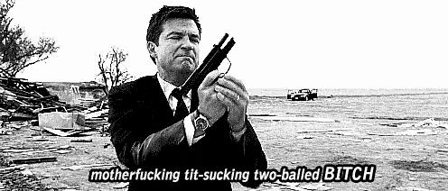 a man in a suit and tie is holding a gun with the words motherfucking tit-sucking two-balled bitch below him