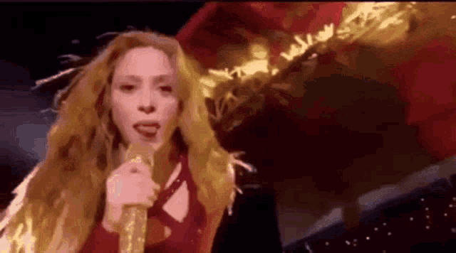 a woman is singing into a microphone on a stage while holding a red flag .
