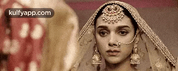 a woman in a wedding dress with a nose ring and veil is looking at the camera .