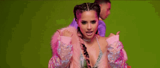 a woman in a pink fur coat is standing next to a man in a purple jacket on a green background .