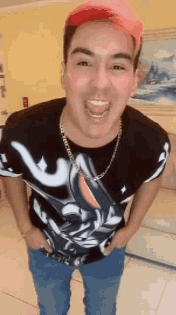 a man with pink hair is wearing a black shirt and blue jeans and making a funny face .