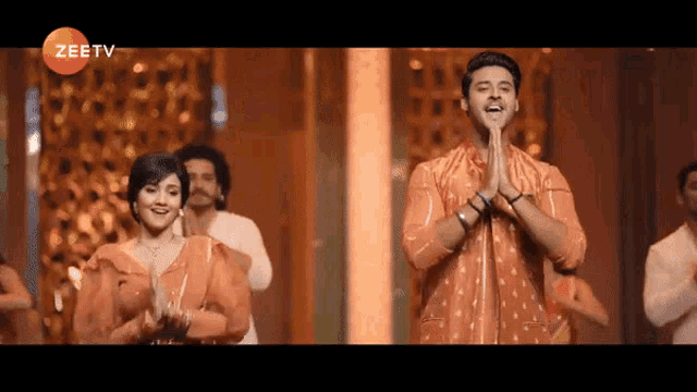 a man and a woman are dancing on a stage with a zee tv logo in the background .