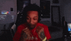 a man wearing headphones is covering his face with his hands while sitting in a chair .