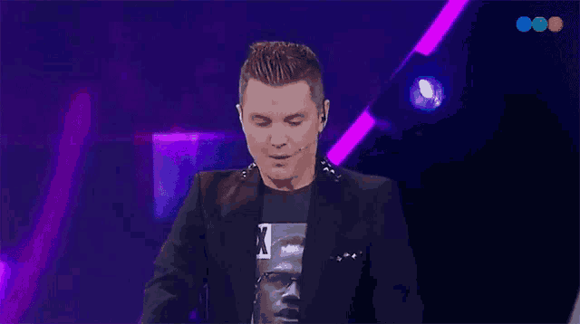 a man wearing a black jacket and a t-shirt with the letter k on it