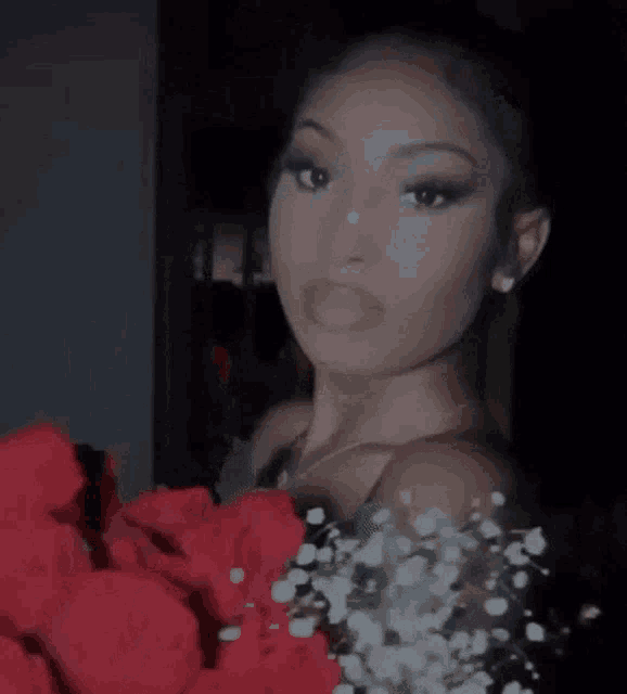 a close up of a woman holding a bouquet of red roses .