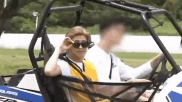 a man wearing sunglasses is sitting in a atv with another man .