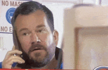 a man talking on a cell phone in front of a sign that says no mask