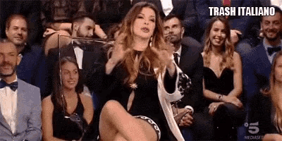 a woman in a black dress is sitting on the floor in front of a crowd .