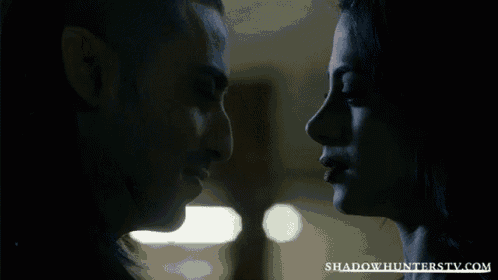 a close up of a man and woman kissing with the website shadowhunterstv.com visible in the corner