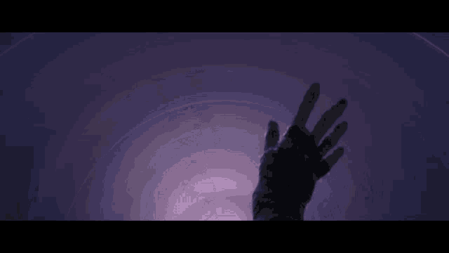 a person 's hand is reaching out towards a purple sky