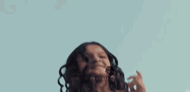 a woman with long curly hair is wearing overalls and smiling .