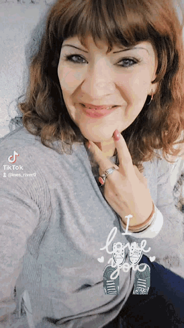 a woman wearing a grey sweater and a ring is smiling for the camera