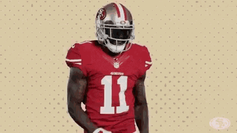 a football player in a red uniform is holding a football in his hands .