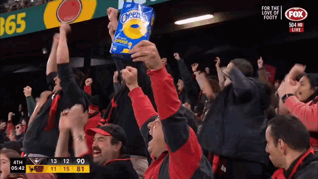 a pack of cheetos is being held in the air by a crowd