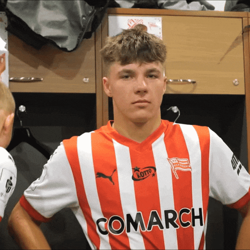 a young man wearing a red and white striped comarch shirt