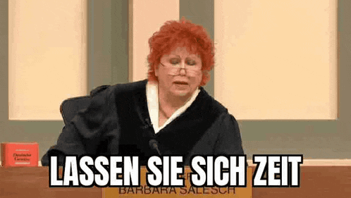 a judge with red hair and glasses is sitting in front of a microphone in a courtroom .