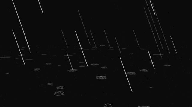 rain is falling on a black background and making circles in the water