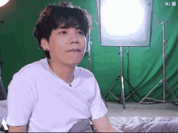 a young man is sitting in front of a green screen .