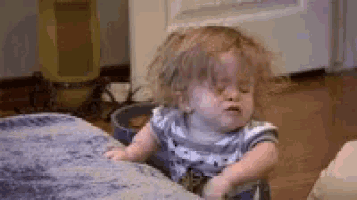 a baby is sitting on a couch making a funny face