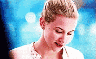 a woman with blonde hair in a bun is smiling and looking down .