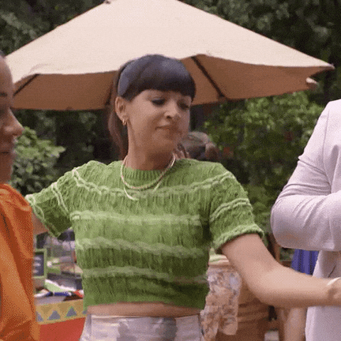 a woman in a green crop top is dancing with a man in a white shirt .
