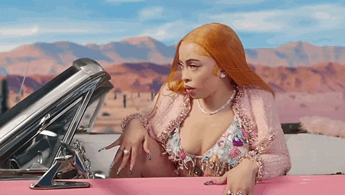 a woman with red hair is sitting in a pink convertible car